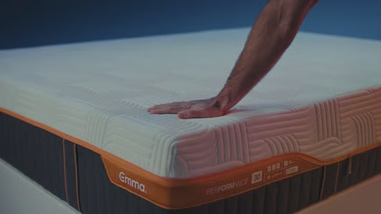 A hand gently pressing the quilted Emma mattress surface